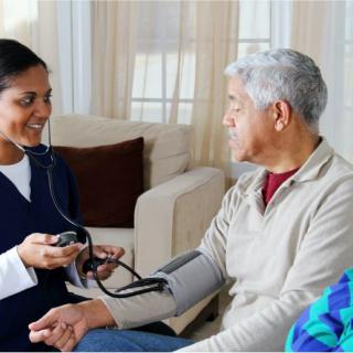 A healthcare professional measuring a patient's blood pressure during a home visit.