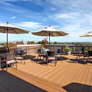 A spacious outdoor patio with tables and umbrellas, offering a scenic view under a clear blue sky.