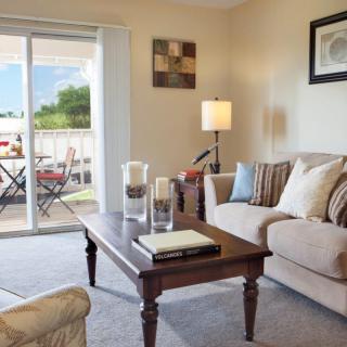 A cozy living room with a beige sofa, wooden coffee table, and a sliding glass door leading to a patio.