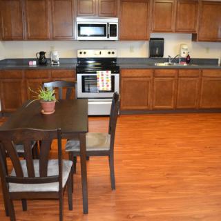 A kitchen with wooden cabinets and a small dining table with chairs.