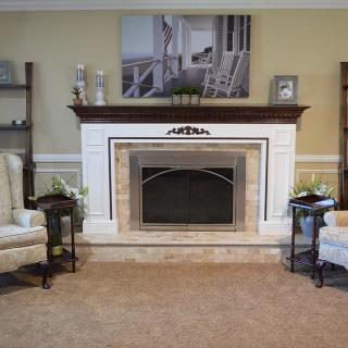 A cozy living room featuring a traditional fireplace flanked by comfortable armchairs and decorative shelves.