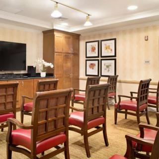 A small conference room with neatly arranged chairs facing a television and decorated walls.