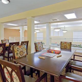 A dining area featuring a large table and chairs, with warm lighting.