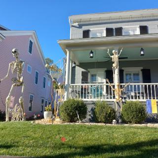 A festive Halloween display featuring skeleton decorations in front of a charming house.