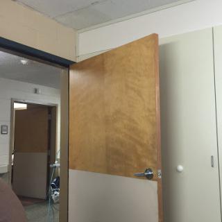 An open door in an office setting, showcasing a wooden finish.