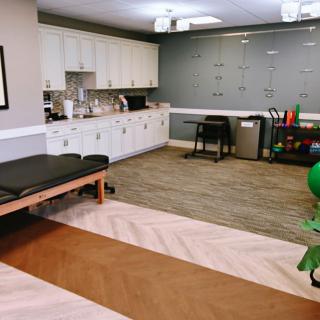 A well-equipped physical therapy clinic with various exercise tools and a treatment table.