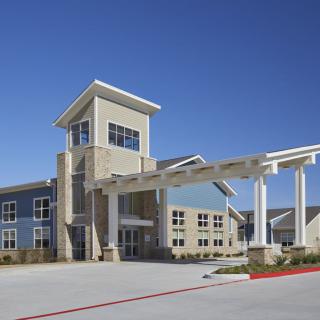 A modern building with a prominent entrance and clear blue sky in the background.