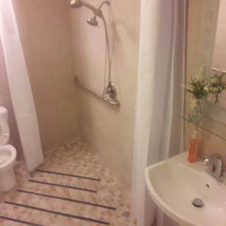 A small bathroom featuring a shower area, sink, and toilet with decorative tiles and toiletries.
