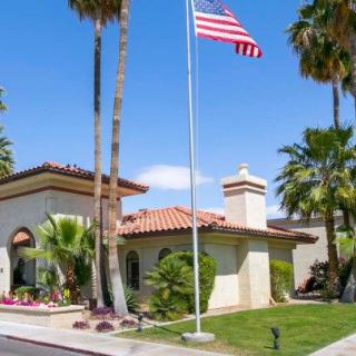 A house with an American flag and palm trees under a clear, sunny sky.