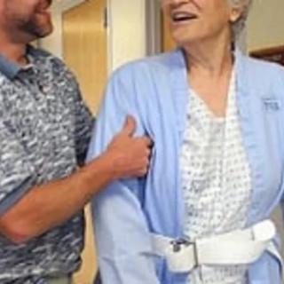 A caregiver assisting an elderly woman in a healthcare setting.