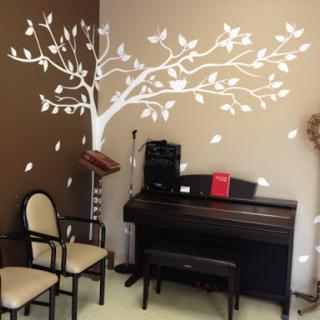 A cozy music room featuring a decorative tree mural on the wall and a piano.