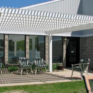 An outdoor patio with a pergola and seating area next to a building.