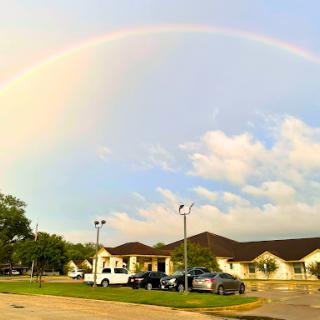 A beautiful rainbow arches over a serene scene with clouds and buildings.