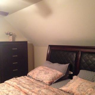 A cozy bedroom with a bed and dresser under a sloped ceiling.