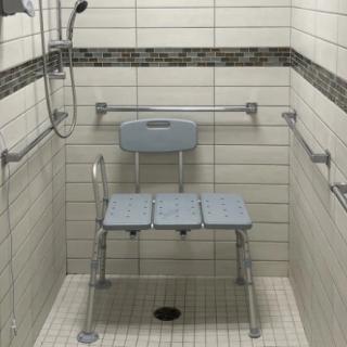An accessible shower setup with a shower chair and grab bars for safety.