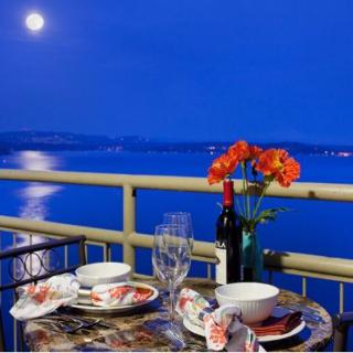 A romantic dinner setup on a balcony overlooking the moonlit water.