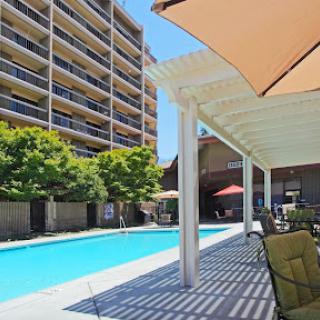 A serene swimming pool area surrounded by a modern apartment building, perfect for relaxation on a sunny day.