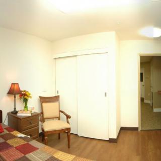A cozy bedroom with a chair, lamp, and closet.