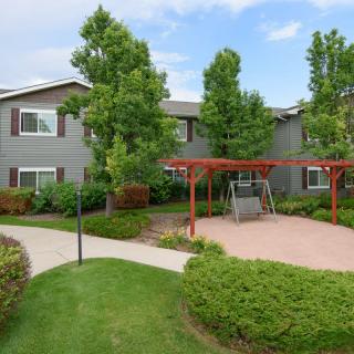 A well-maintained apartment complex with lush landscaping and outdoor swing seating.