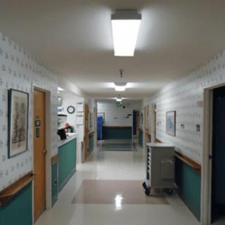 An empty hospital hallway with bright overhead lighting and doors along the sides.