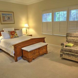 A cozy bedroom with a wooden bed, armchair, and warm lighting.