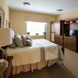 A cozy bedroom with a neatly made bed, decorative pillows, and warm lighting.