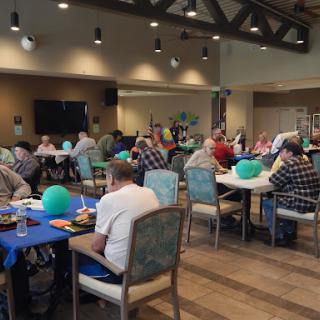 A lively community gathering featuring people enjoying food and conversation around tables.