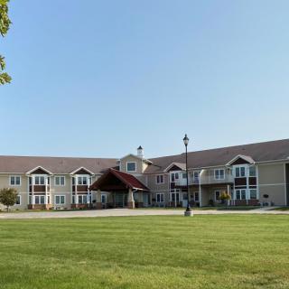A large residential building with a well-maintained lawn and a covered entrance.