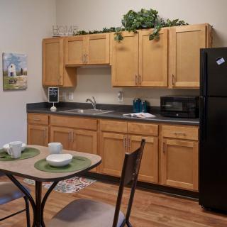A cozy kitchen and dining area featuring wood cabinets, black appliances, and a small dining table with place settings.
