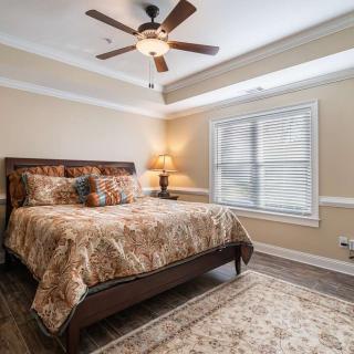 A cozy bedroom with a large bed, ceiling fan, and natural lighting through the window.
