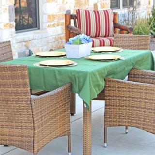 A cozy outdoor dining setup with wicker chairs and a green tablecloth, ready for a meal on the patio.