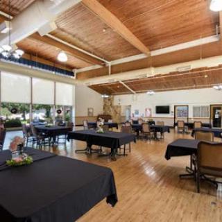 A spacious indoor dining area with black tablecloths and a wooden ceiling, ideal for gatherings and events.