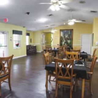 An empty dining room with wooden tables and chairs, ceiling fans, and a wooden floor.