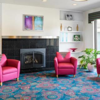 A colorful living room featuring red chairs, a fireplace, and decorative shelves.