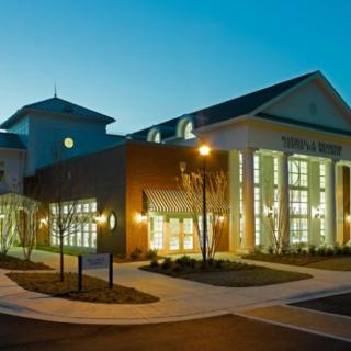 A well-lit library building at night with glowing windows and modern architecture.
