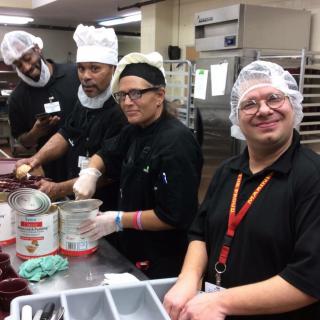 A group of chefs working together in a kitchen, preparing food with focus and teamwork.