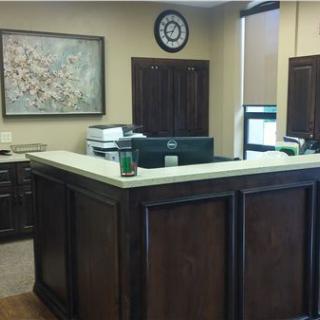 An office reception area with a wooden counter and office equipment.