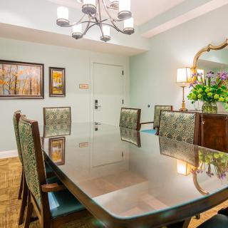 A well-designed dining room with a large table, elegant chairs, and a chandelier overhead.