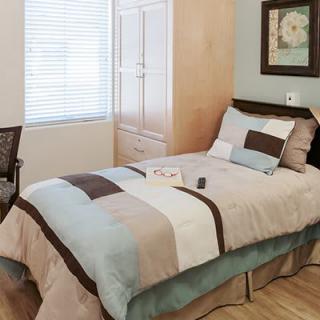 A neatly arranged bedroom with a single bed, wardrobe, and decor.