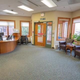 A spacious office reception area with a desk, chairs, and large windows.
