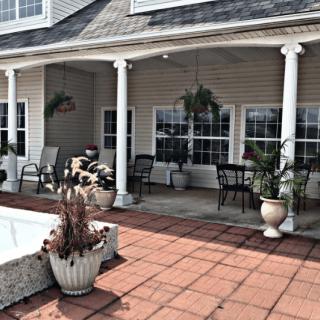 A cozy outdoor patio area with seating, tables, and decorative potted plants.