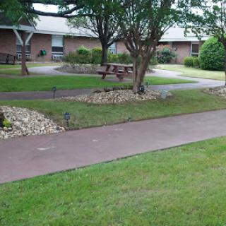 A peaceful park area featuring a winding pathway, lush greenery, and comfortable benches for relaxation.