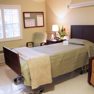 A clean and minimalist hospital room with a single bed and simple furnishings.