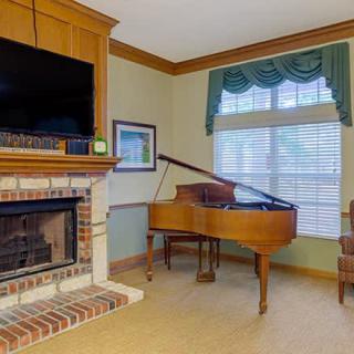 A cozy living room featuring a fireplace and a grand piano by the window.