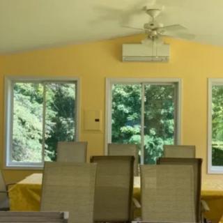 A bright dining room with a table and chairs, illuminated by natural light streaming through large windows.