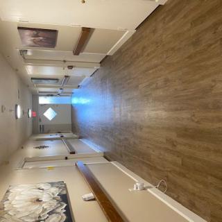 A long hallway featuring wooden flooring, artwork on the walls, and multiple doors.