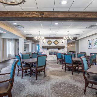 A spacious and elegantly designed dining room with multiple tables and chairs, featuring stylish lighting fixtures and decor.