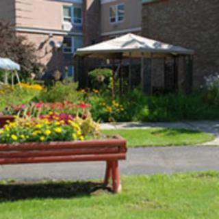 A lush garden area featuring vibrant flowers and a wooden bench in front of a building.