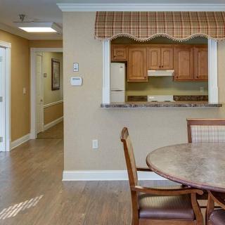 A cozy kitchen and dining area with wood flooring, featuring a round table and chairs.