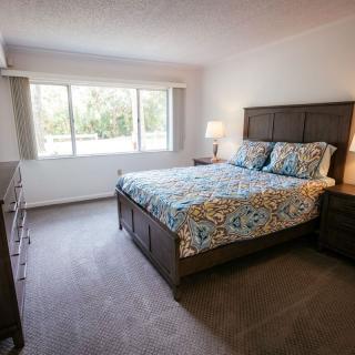 A cozy bedroom with a large bed, side tables, and a window allowing natural light.
